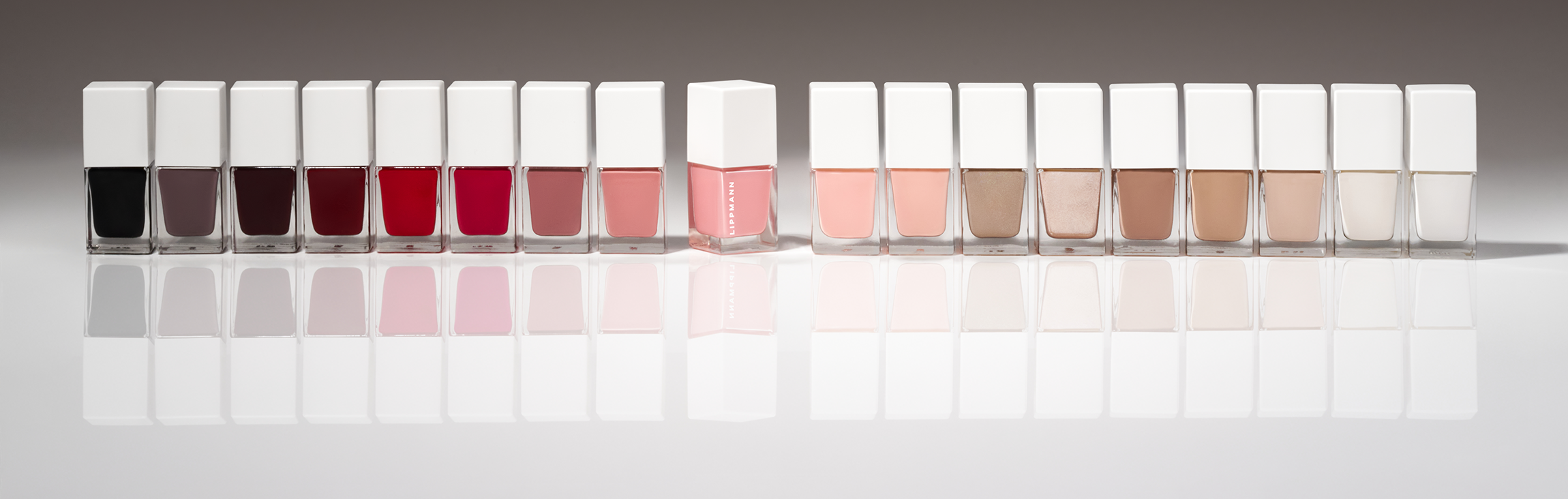 straight line of deborah lippmann nai polish in rainbow order sitting on white table surface